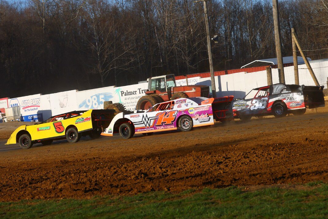 DIRTcar UMP Sportsman cars race side by side during a heat race at a dirt racing event. 