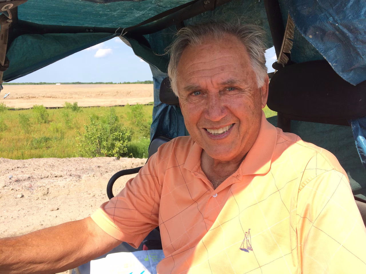 Glenn Donnelly — who founded DIRTcar in 1976 — smiles for the camera from his golf cart. 