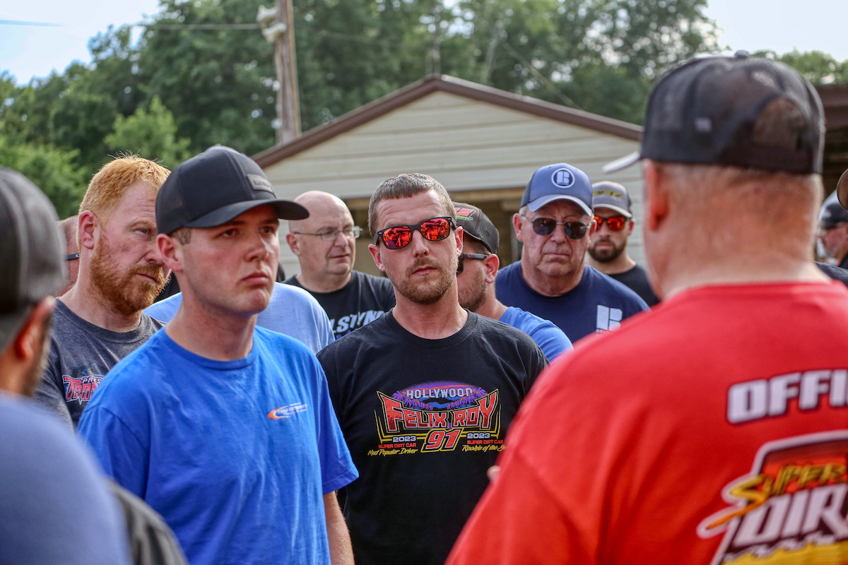 A Super DIRTcar Series official addresses drivers at a driver's meeting before a dirt racing event. 